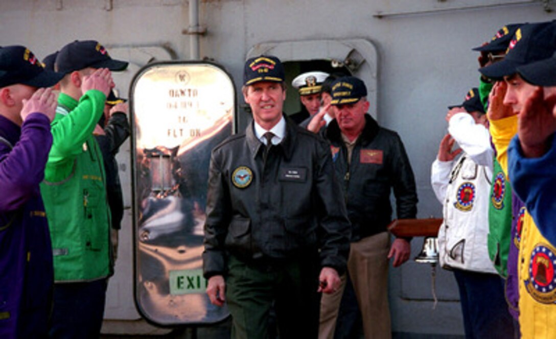 Secretary of Defense William S. Cohen (center) passes through the sideboys on the flight deck of the aircraft carrier USS Independence (CV 62), while the ship is moored in Yokosuka, Japan, on Jan. 21, 1998. Cohen is visiting the ship to speak to the crew and announce the deployment of the Independence Battle Group to the Persian Gulf to relieve the USS Nimitz Battle Group. Sideboys are part of the Navy tradition used in honoring visiting dignitaries. 