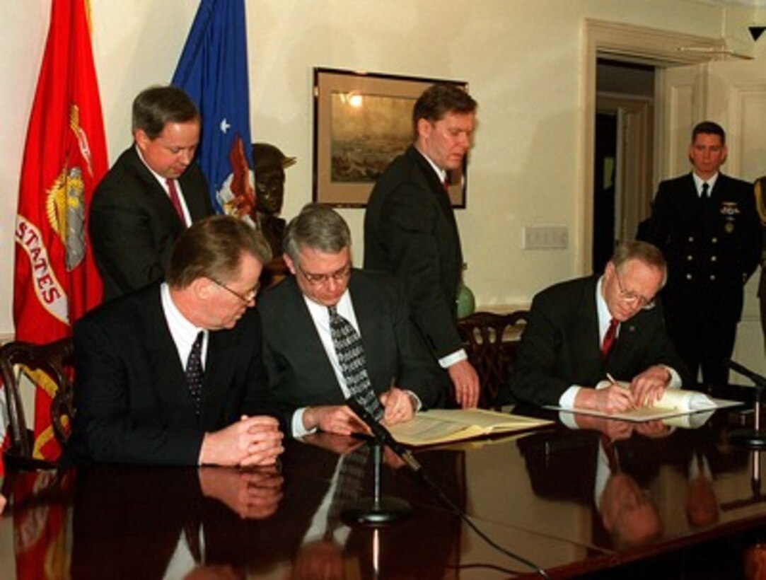 President Guntis Ulmanis (left), of the Republic of Latvia, looks on as Deputy Secretary of Defense John J. Hamre (center) and Minister of Defense Talavs Jundzis (right), of the Republic of Latvia, sign a General Agreement on the Security of Military Information in the Pentagon on Jan. 15, 1998. 