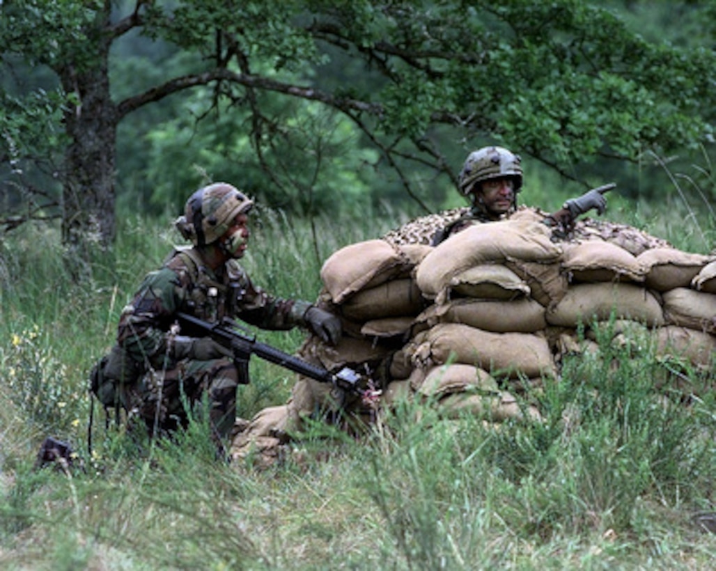 U.S. Air Force Master Sgt. Oscar King (right) directs a team member to move forward as Staff Sgt. Jeff Berg (left) keeps watch as their team competes in the combat tactics scenario during Air Mobility Rodeo 98 at McChord Air Force Base, Wash., on June 22, 1998. Rodeo 98 tests the flight and ground skills of aircrews as well as the related skills of special tactics, security forces, aerial porters, aeromedical evacuation and maintenance members. The goal of the international airlift-tanker competition is to develop and improve techniques and procedures that enhance air mobility operations. King and Berg are attached to the 6th Security Forces Squadron, MacDill Air Force Base, Fla. 