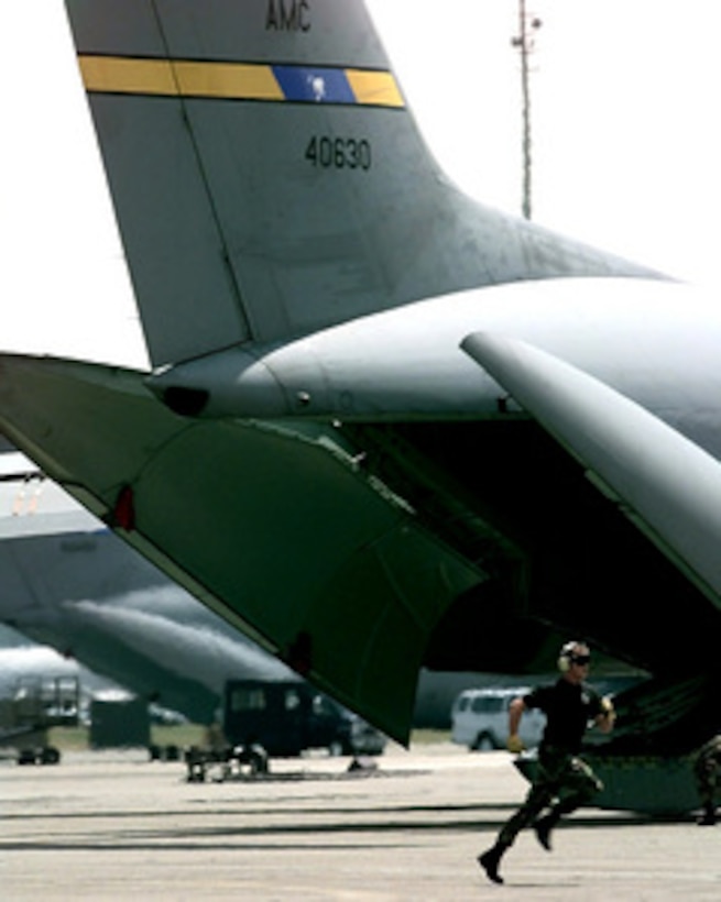 Senior Airman Kory Aschenbrenner sprints from the back of a C-141 Starlifter after loading the plane during the engine running on load/off load competition of Air Mobility Rodeo 98 at McChord Air Force Base, Wash., June 22, 1998. The engine running on load/off load competition requires the team to load a truck and two trailers and secure them for flight. After loading, the crew has to release and remove the equipment from the aircraft. They are judged on safety and speed. Rodeo 98 tests the flight and ground skills of aircrews as well as the related skills of special tactics, security forces, aerial porters, aeromedical evacuation and maintenance members. The goal of the international airlift-tanker competition is to develop and improve techniques and procedures that enhance air mobility operations. Aschenbrenner is attached to the 437th Aerial Port Squadron, Charleston Air Force Base, S.C. 
