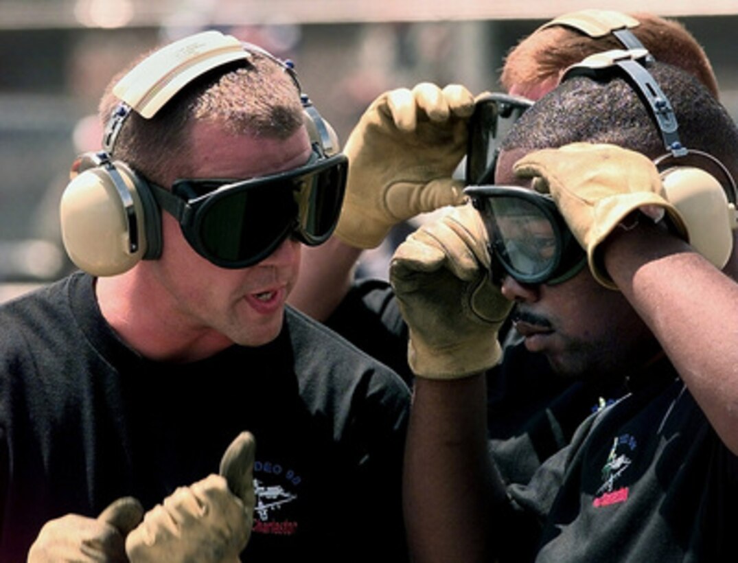 Senior Airman Kory Aschenbrenner (left) discusses strategy with teammate Airman 1st Class Cliff Pinckney Jr. (right) during the engine running on load/off load competition of Air Mobility Rodeo 98 at McChord Air Force Base, Wash., June 22, 1998. The engine running on load/off load competition requires the team to load a truck and two trailers and secure them for flight. After loading, the crew has to release and remove the equipment from the aircraft. They are judged on safety and speed. Rodeo 98 tests the flight and ground skills of aircrews as well as the related skills of special tactics, security forces, aerial porters, aeromedical evacuation and maintenance members. The goal of the international airlift-tanker competition is to develop and improve techniques and procedures that enhance air mobility operations. Aschenbrenner and Pinckney are attached to the 437th Aerial Port Squadron, Charleston Air Force Base, S.C. 