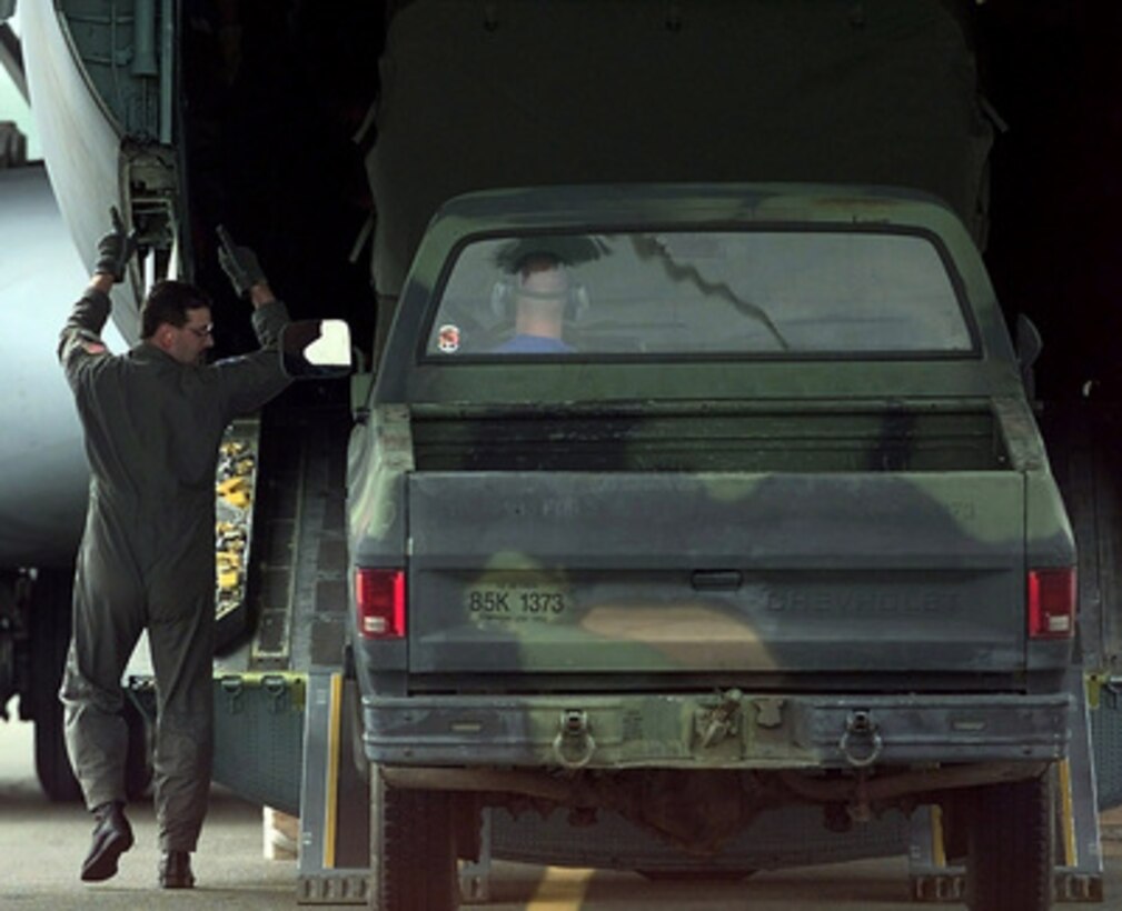 A loadmaster from the 305th Air Mobility Wing, McGuire Air Force Base, N.J., marshals a truck into the back of a C-141 Starlifter during the engine running on load/off load competition of Air Mobility Rodeo 98 at McChord Air Force Base, Wash., June 22, 1998. The engine running on load/off load competition requires the team to load a truck and two trailers and secure them for flight. After loading, the crew has to release and remove the equipment from the aircraft. They are judged on safety and speed. Rodeo 98 tests the flight and ground skills of aircrews as well as the related skills of special tactics, security forces, aerial porters, aeromedical evacuation and maintenance members. The goal of the international airlift-tanker competition is to develop and improve techniques and procedures that enhance air mobility operations. 