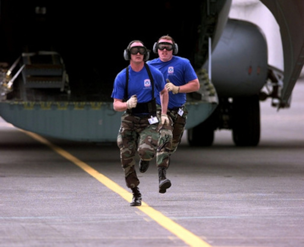 Tech. Sgt. Dale Wenn and Senior Airman Bart Larson run from the back of a C-141 Starlifter after completing the engine running on load/off load competition of Air Mobility Rodeo 98 at McChord Air Force Base, Wash., June 22, 1998. The engine running on load/off load competition requires the team to load a truck and two trailers and secure them for flight. After loading, the crew has to release and remove the equipment from the aircraft. They are judged on safety and speed. Rodeo 98 tests the flight and ground skills of aircrews as well as the related skills of special tactics, security forces, aerial porters, aeromedical evacuation and maintenance members. The goal of the international airlift-tanker competition is to develop and improve techniques and procedures that enhance air mobility operations. Wenn and Larson are attached to the 305th Aerial Port Squadron, McGuire Air Force Base, N.J. 