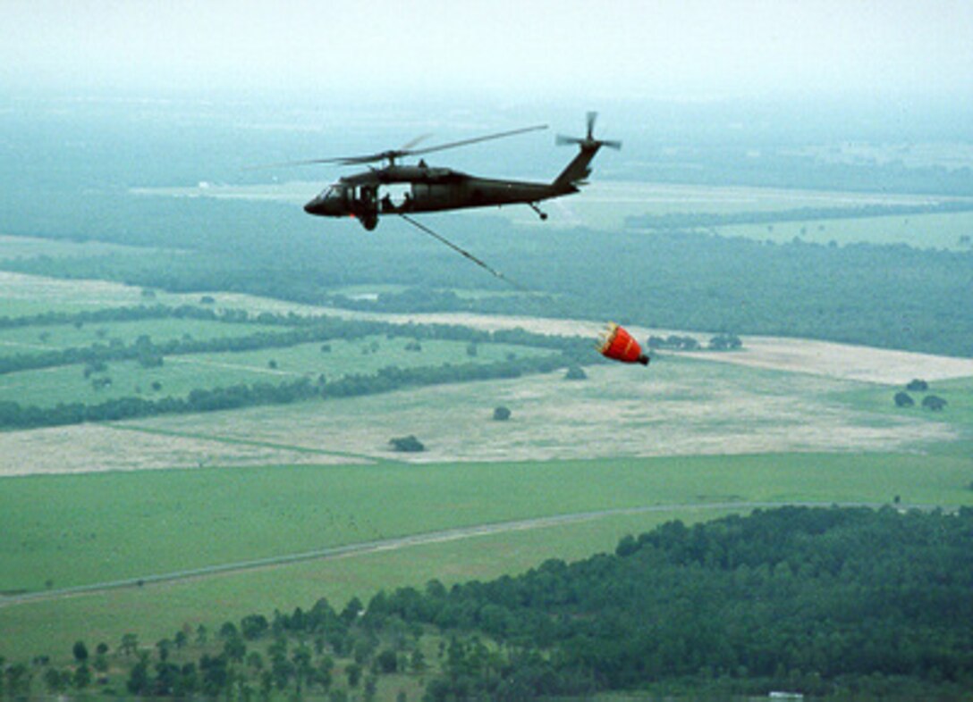 A Florida National Guard UH-60 Blackhawk helicopter carries a 700 gallon water bucket used in fighting forest fires en route to fires outside Daytona, Fla., on July 4, 1998. 