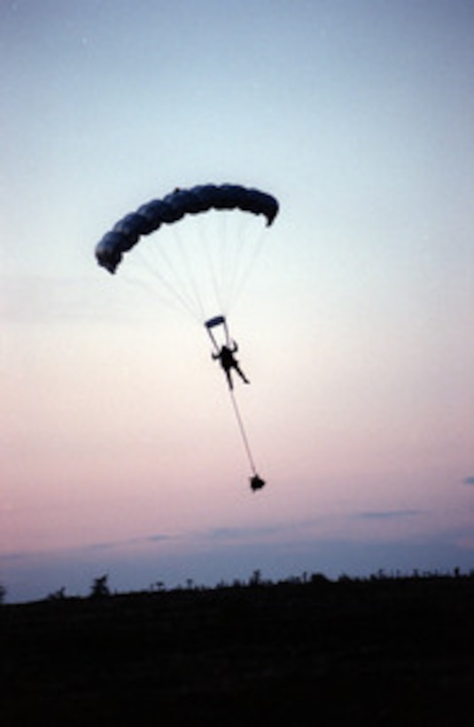 Sgt. Michael Tavaska glides his parachute down into a clearing within the woods near Stephenville, Newfoundland. The jump from a CH-46 Sea Knight helicopter was in preparation for the "invasion" during Unified Spirit '98, a maritime combined operational training exercise. The exercise includes forces from Canada, Denmark, the United Kingdom, France, the United States, and other NATO nations. It provides effective, realistic training to improve the skills needed during a NATO led peacekeeping support operation. 
