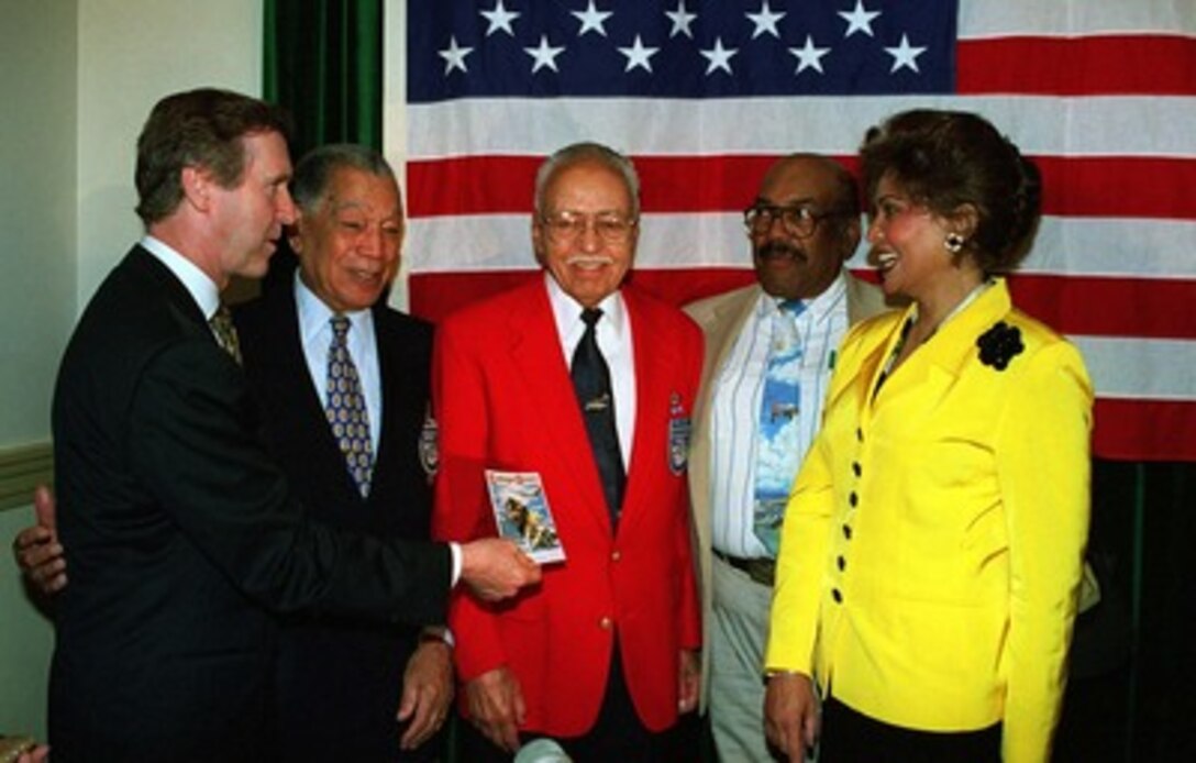 Secretary of Defense William S. Cohen (left) shows his wife Janet (right) a memento presented to him by members of the legendary Tuskeegee Airmen on May 16, 1998. With Secretary and Mrs. Cohen are from left to right Col. Lee Archer, Lt. Col. Howard Baugh, and Lt. Col. Charles Bussey. Cohen visited Norfolk State University to kick off the nation's 50th anniversary observance of President Harry S. Truman's executive order desegregating the armed forces. 