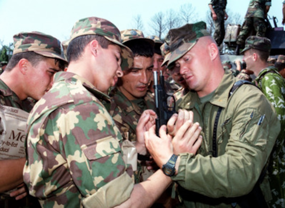 U.S. Marine 2nd Lt. Michael Hall (right) shows Kazakstan soldiers how to break down a 9 mm pistol during a safety briefing at Landing Zone Bluebird on June 4, 1998, as part of Exercise Cooperative Osprey '98 at Marine Corps Base, Camp Lejeune, N.C. Cooperative Osprey '98 is a Partnership for Peace situational training exercise designed to improve the interoperability of NATO and partner nations through the practice of combined peacekeeping and humanitarian relief operations. Partner nations include Albania, Bulgaria, Estonia, Georgia, Kazakstan, Kyrgyzstan, Latvia, Lithuania, Moldova, Poland, Romania, Ukraine, and Uzbekistan. Participating NATO nations include Canada, The Netherlands, and the United States. 