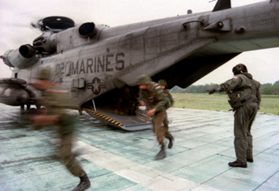 Polish soldiers from Training Company 1 run out of a CH-53E Super Stallion helicopter to set up a tactical perimeter at Landing Zone Bluebird during Exercise Cooperative Osprey '98 on June 6, 1998, at Marine Corps Base, Camp Lejeune, N.C. Training Company 1, consisting of U.S. Marines, Polish, and Lithuanian soldiers, is being taught a wide variety of defensive and offensive urban tactics. Cooperative Osprey '98 is a Partnership for Peace situational training exercise designed to improve the interoperability of NATO and partner nations through the practice of combined peacekeeping and humanitarian relief operations. Partner nations include Albania, Bulgaria, Estonia, Georgia, Kazakstan, Kyrgyzstan, Latvia, Lithuania, Moldova, Poland, Romania, Ukraine, and Uzbekistan. Participating NATO nations include Canada, The Netherlands, and the United States. 