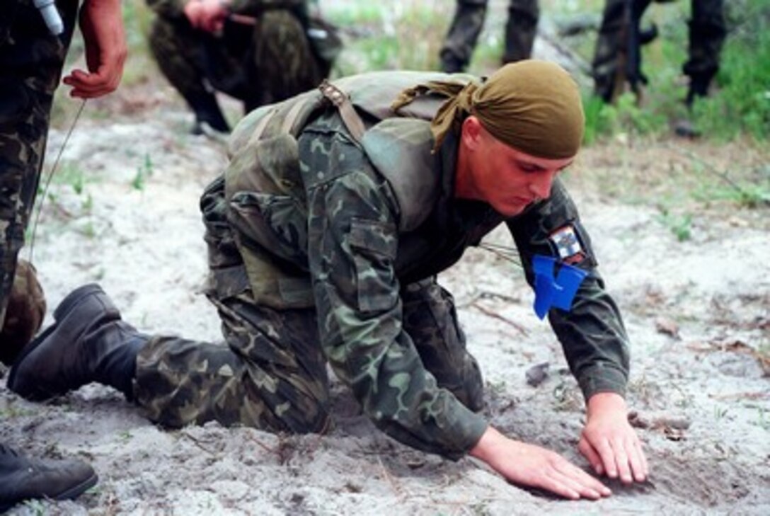 A Ukrainian soldier uncovers a buried simulated mine as part of his training during Exercise Cooperative Osprey '98 on June 6, 1998, at Marine Corps Base, Camp Lejeune, N.C. The Ukrainian soldiers are being shown methods of identifying, marking and reporting mines, unexploded ordnance, and improvised explosive devices. Cooperative Osprey '98 is a Partnership for Peace situational training exercise designed to improve the interoperability of NATO and partner nations through the practice of combined peacekeeping and humanitarian relief operations. Partner nations include Albania, Bulgaria, Estonia, Georgia, Kazakstan, Kyrgyzstan, Latvia, Lithuania, Moldova, Poland, Romania, Ukraine, and Uzbekistan. Participating NATO nations include Canada, The Netherlands, and the United States. 