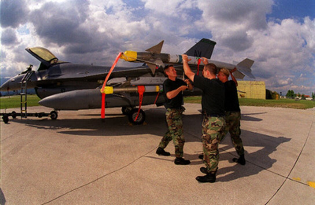 Airman 1st Class Shane Hickman (left), Staff Sgt. Scott Centobene (center), and Airman 1st Class Vincent Horn (right), load an AIM-9 Sidewinder missile onto an F-16 Fighting Falcon at Aviano Air Base, Italy, on June 15, 1998, in preparation for Exercise Determined Falcon. Forces from the United States European Command participated in and supported the one-day NATO exercise. NATO conducted Determined Falcon over Albania and the Former Yugoslav Republic of Macedonia with the agreement of those two governments. The objective of this exercise was to demonstrate NATO's capability to project power rapidly into the region. The F-16 is attached to the 555th Fighter Squadron, 31 Fighter Wing at Aviano. 