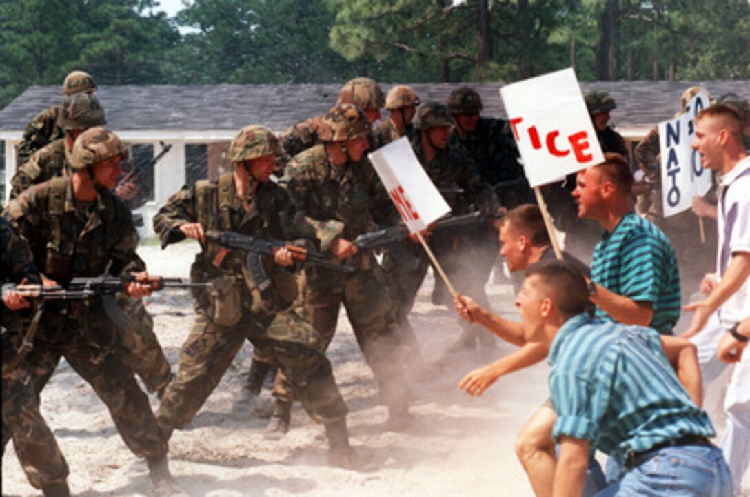 Lithuanian soldiers from Training Company 1 create a barrier in order to control a mob of role playing outraged civilians as part of situational training during Exercise Cooperative Osprey '98 on June 8, 1998, at Marine Corps Base, Camp Lejeune, N.C. Training Company 1, formed for the exercise, consists of U.S. Marines, Polish, and Lithuanian soldiers who are receiving intensive training in non-combatant operations such as medical evacuations and civil disturbances. Cooperative Osprey '98 is a Partnership for Peace situational training exercise designed to improve the interoperability of NATO and partner nations through the practice of combined peacekeeping and humanitarian relief operations. Partner nations include Albania, Bulgaria, Estonia, Georgia, Kazakstan, Kyrgyzstan, Latvia, Lithuania, Moldova, Poland, Romania, Ukraine, and Uzbekistan. Participating NATO nations include Canada, The Netherlands, and the United States. Hale is attached to the 3rd Battalion, 8th Marine Regiment. 