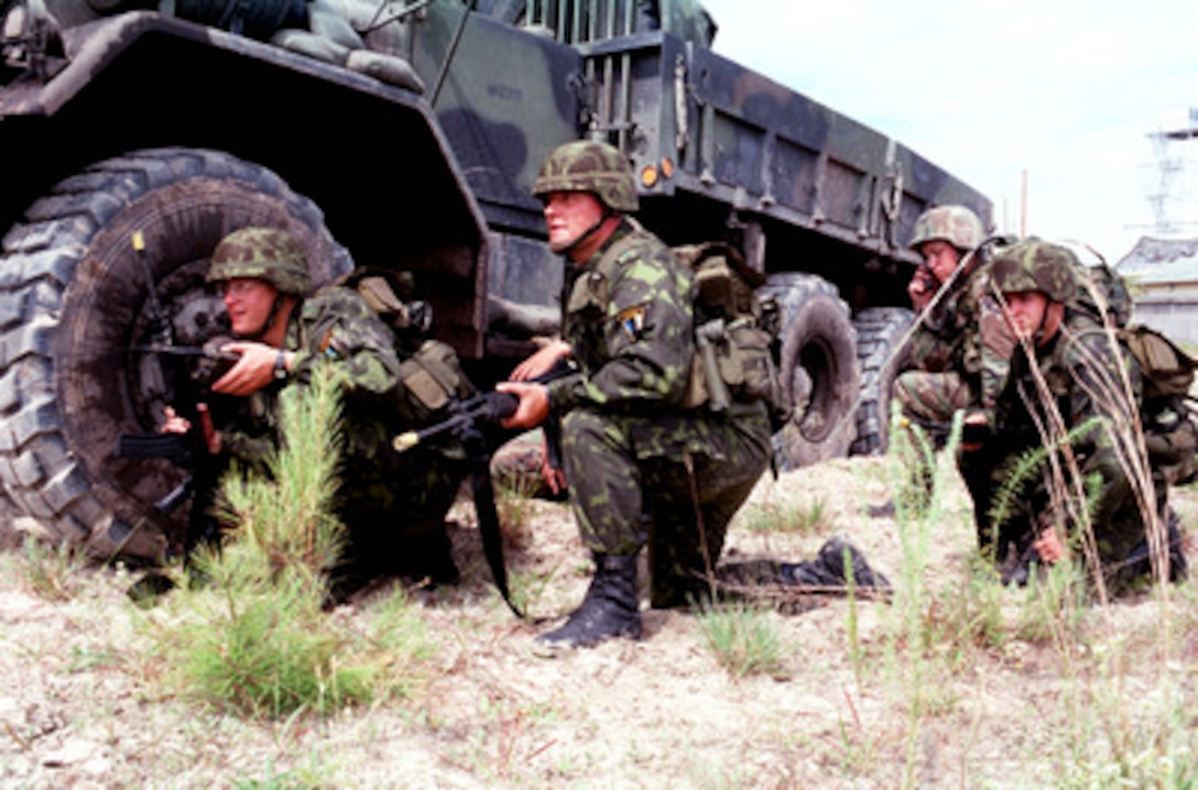 Estonian soldiers crouch alongside an M923 5 ton truck as they wait for further orders during Convoy Operations as part of situational training during Exercise Cooperative Osprey '98 on June 10, 1998, at Marine Corps Base, Camp Lejeune, N.C. Cooperative Osprey '98 is a Partnership for Peace situational training exercise designed to improve the interoperability of NATO and partner nations through the practice of combined peacekeeping and humanitarian relief operations. Partner nations include Albania, Bulgaria, Estonia, Georgia, Kazakstan, Kyrgyzstan, Latvia, Lithuania, Moldova, Poland, Romania, Ukraine, and Uzbekistan. Participating NATO nations include Canada, The Netherlands, and the United States. 