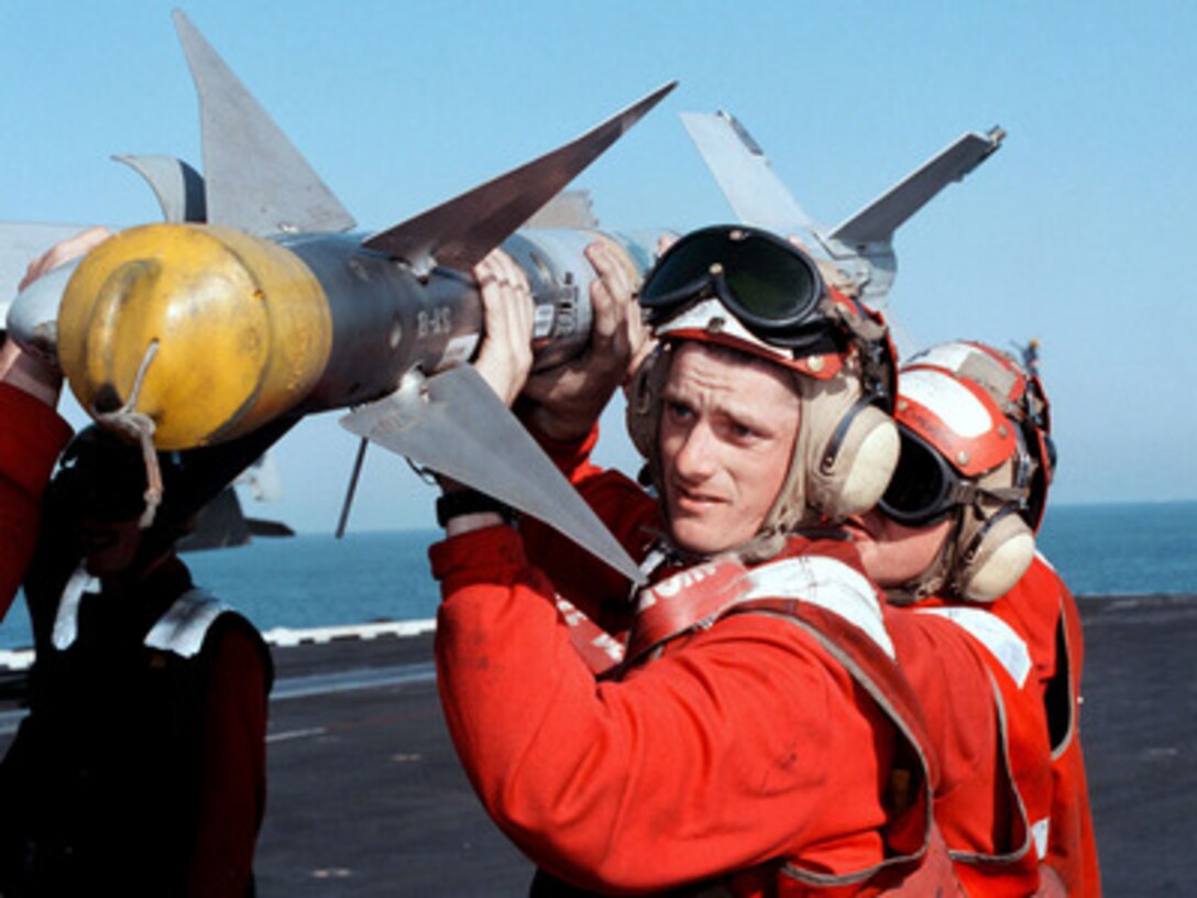 Aviation ordnancemen load an AIM-9 Sidewinder air-to-air missile onto an F/A-18C Hornet aboard the aircraft carrier USS George Washington (CVN 73 as the ship steams in the Persian Gulf on Feb. 19, 1998. The Washington battle group is operating in the Persian Gulf in support of Operation Southern Watch which is the U.S. and coalition enforcement of the no-fly-zone over Southern Iraq. 