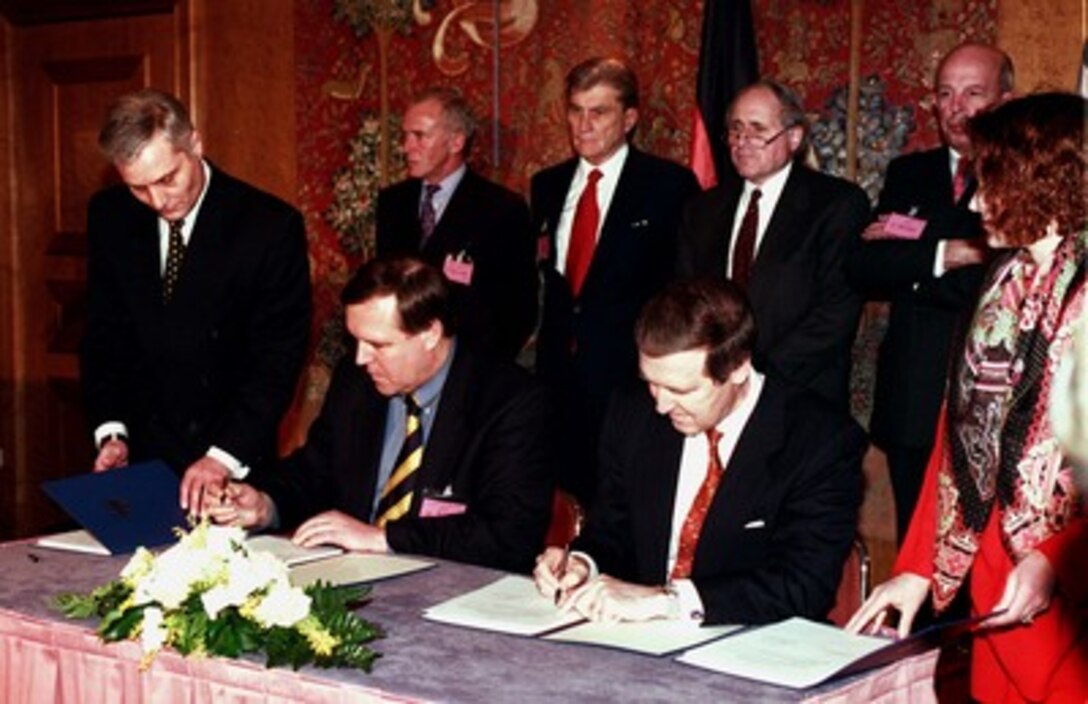 German Minister of Defense Volker Ruehe (seated left) and Secretary of Defense William S. Cohen (seated right) sign the Follow-on Implementing Amendment to the 1983 Agreement on Cooperative Measures for Enhancing Air Defense for Central Europe in Munich, Germany, on Feb. 7, 1998, during the Werkunde Conference. The agreement permits the transfer of title of 21 U.S.-owned and German manned Roland weapon systems and 12 Patriot fire units to the Germans. Standing behind Cohen is Sen. Carl Levin, (right) (D-Mich.), and Sen. John W. Warner (center), (R-Va.). 