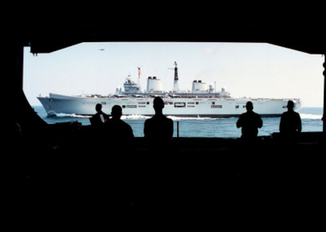 Crew members aboard the U.S. Navy aircraft carrier USS George Washington (CVN 73) watch from the ship's hangar bay as the British Royal Navy aircraft carrier HMS Invincible (CVS-R05) comes alongside as the two ships operate in the Persian Gulf on March 5, 1998. Both carriers are deployed to the Persian Gulf in support of Operation Southern Watch. 
