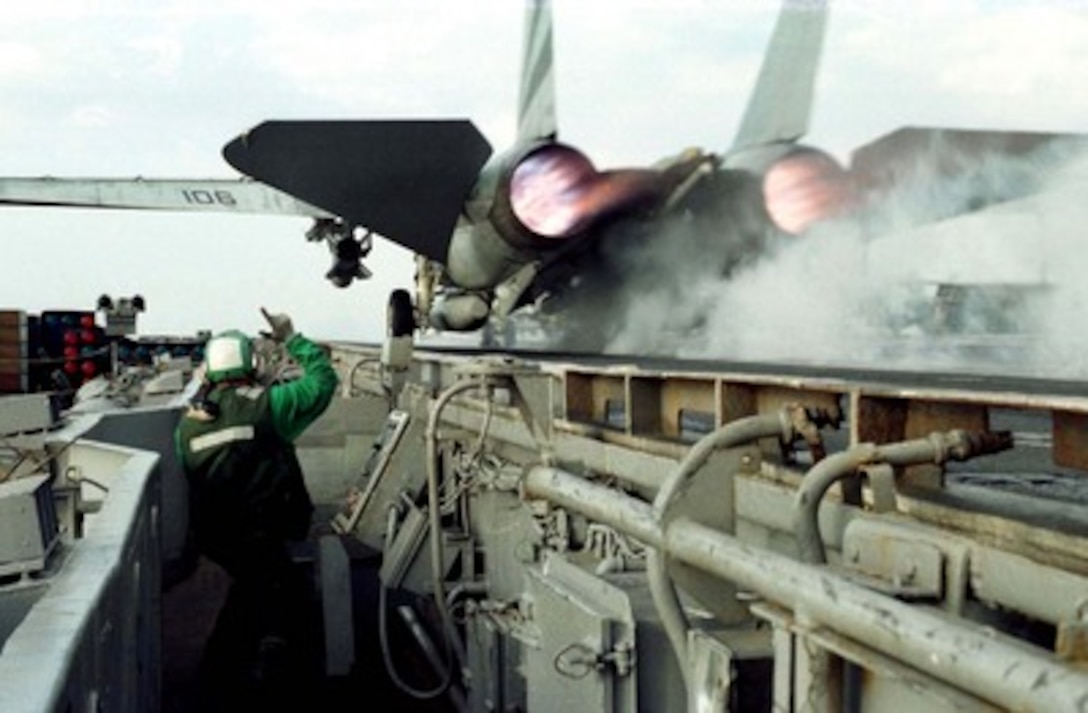 Petty Officer 3rd Class Joshua Schwandt signals a clear launch after an F-14 Tomcat roars over his head from the port side catapult of the USS Independence (CV 62) as the ship operates in the Persian Gulf on Feb. 22, 1998. Independence and its embarked Carrier Air Wing 5 are on station in the Persian Gulf in support of Operation Southern Watch which is the U.S. and coalition enforcement of the no-fly-zone over Southern Iraq. Schwandt, from Sacramento, Calif., is a Navy aviation boatswain's mate launch and recovery equipment operator. 