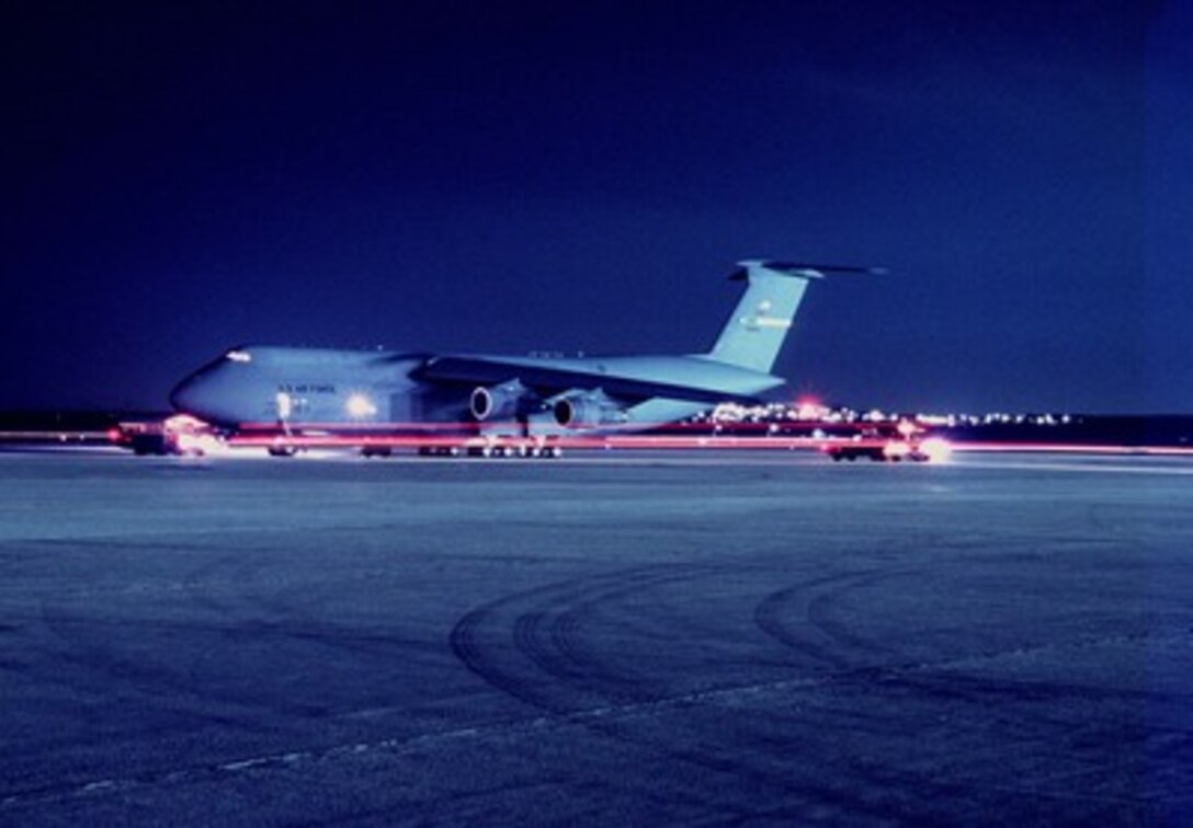 Headlights and taillights of vehicles leave streaks of red as they pass by a U.S. Air Force C-5B Galaxy sitting on the ramp at March Air Reserve Base, Calif., on Feb. 26, 1997. The Galaxy is loading personnel and equipment deploying to the Persian Gulf area of operations as part of a force augmentation in Southwest Asia. The Galaxy is deployed from the 60th Airlift Wing, Travis Air Force Base, Calif. 