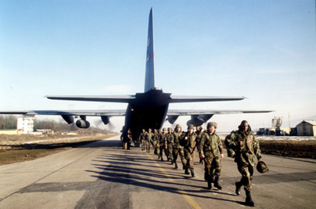 U.S. military personnel walk single file off of a U.S. Air Force C-130 Hercules at Tuzla Air Base, Bosnia and Herzegovina, on Feb. 24, 1998, after a flight from Ramstein Air Base, Germany. The aircraft is bringing in personnel, equipment and supplies to support the Stabilization Force in Operation Joint Guard. The Hercules and its crew are deployed from the 40th Airlift Squadron, Dyess Air Force Base, Texas. 