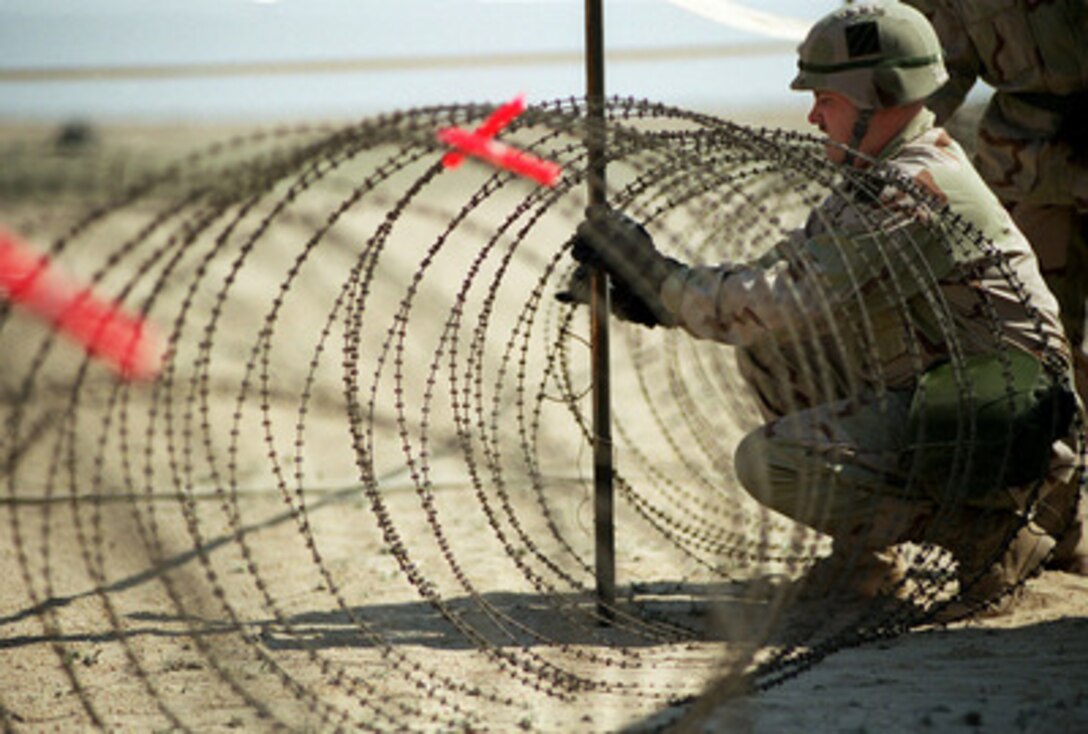 U.S. Army Sgt. Troy Brayton works on coils of concertina wire at a U.S. Army camp in the Kuwaiti desert on March 2, 1998. Brayton is attached to the 3rd Forward Support Battalion, Fort Stewart, Ga., which is deployed to Kuwait as part of a force augmentation in Southwest Asia. 