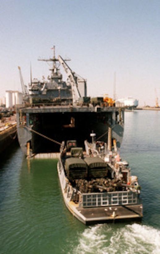 A U.S. Marine Corps ambulance drives off the deck of a U.S. Navy Landing Craft, Utility into the well deck of the USS Ashland (LSD 48) as the ship sits alongside the pier in Kuwait City, Kuwait, March 3, 1998. The Ashland is loading equipment as part of a force augmentation in Southwest Asia. The Ashland is homeported in Little Creek, Va. 