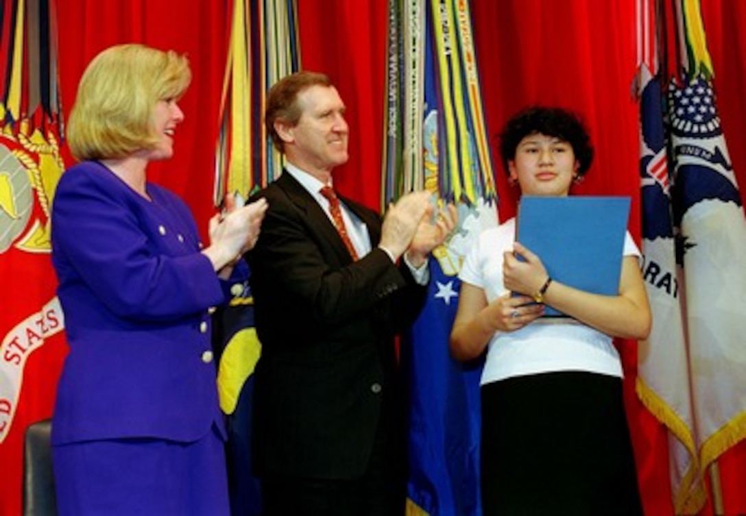Tipper Gore (left), wife of Vice President Al Gore, and Secretary of Defense William Cohen (center) applaud Erika Martinez, of the John Tyler Elementary School, Washington, D. C., following her reading of her award winning essay "Women Have Made a Difference." The essay reading was part of the March 5, 1998, Pentagon observance of National Women's History Month which featured a keynote address by Mrs. Gore. 