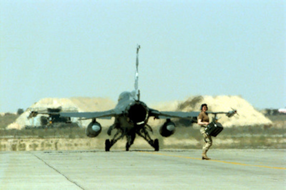 A U.S. Air Force maintenance person walks across the ramp as a F-16 Fighting Falcon taxis out for a combat patrol mission over Southern Iraq on March 5, 1998. Fighting Falcons from the 175th Fighter Squadron are deployed to Kuwait in support of Operation Southern Watch which is the U.S. and coalition enforcement of the no-fly-zone over Southern Iraq. The 175th is deployed from the 114th Fighter Wing, Sioux Falls, South Dakota Air National Guard. 