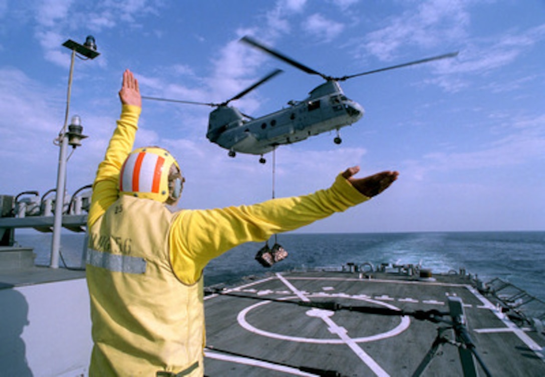 Petty Officer 1st Class John T. Brown directs a CH-46 Sea Knight helicopter toward the flight deck of the USS John S. McCain (DDG 56) during a vertical replenishment on March 5, 1998, in the Persian Gulf. The Arleigh Burke class destroyer is the conducting Maritime Interception Operations the Gulf as part of a force augmentation in the region. The McCain is homeported in Yokosuka, Japan. 