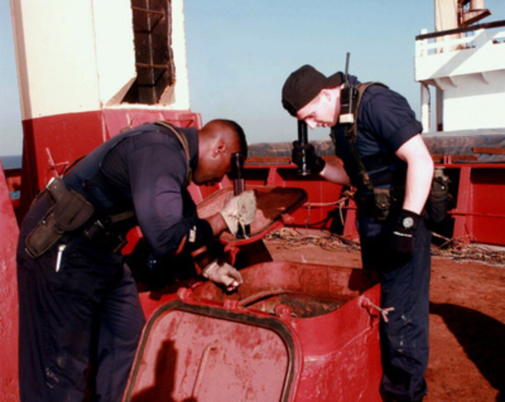 U.S. Navy Petty Officers Second Class Marvin Haynes (left) and Clint Foster (right) peer down one of the scuttles of an Iranian cargo ship prior to entering and inspecting the cargo hold during a maritime interdiction operation in the Persian Gulf on March 6, 1998. Crew members from the USS John S. McCain (DDG-56) boarded and are inspecting the ship for possible contraband. The Arleigh Burke class destroyer is conducting the interception operations as part of a force augmentation in the region. The McCain is home ported in Yokosuka, Japan. 