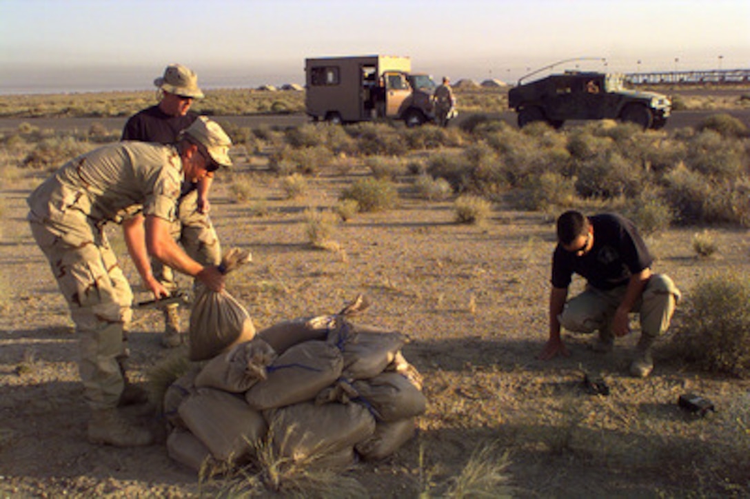 Senior Airman Steve Hallenbeck, Airman 1st Class William Kellum, and Senior Airman Jack Burleigh prepare to detonate an unexploded bomblet found next to the runway at Al Jaber Air Base, Kuwait, on April 24, 1998. These explosive ordinance disposal experts, assigned to the 4406th Operations Group (Provisional), search for Desert Storm era unexploded ordnance on a daily basis. The airmen are deployed to Kuwait in support of Operation Southern Watch, which is the U.S. and coalition enforcement of the no-fly-zone over Southern Iraq. 
