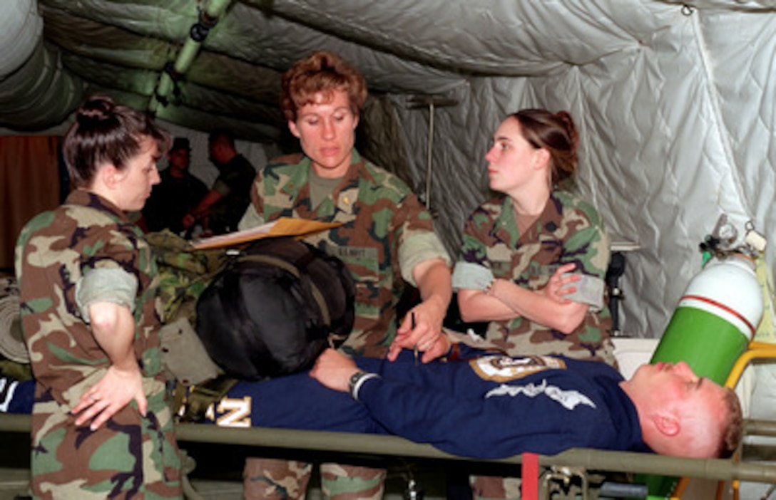 Two Navy corpsmen stand by for direction while a Navy doctor assesses the condition of a sailor role playing as a casualty during a field exercise at Camp Lejeune, N.C., on April 22, 1998. The medical personnel from the Camp Lejeune Naval Hospital are working in the field out of a modern, highly mobile expeditionary tent hospital. The 2nd Medical Battalion, 2nd Force Service Support Group, 2nd Marine Expeditionary Force is conducting the field exercise. 