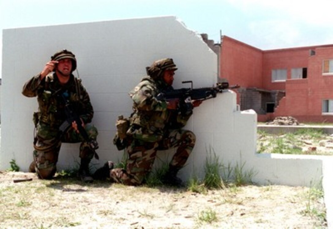 Cpl. Stephen Kramer (left) signals for backup as Lance Cpl. John Pentacola (right) from Bravo Company, 1st Battalion, 8th Marines, fires his M-249 Squad Automatic Weapon at the enemy in the Military Operations in Urban Terrain facility during Urban Warrior Limited Objective Exercise 2 on April 29, 1998, at Camp Lejeune, N.C. Urban Warrior is the U.S. Marine Corps Warfighting Laboratory's series of limited objective experiments examining new urban tactics and experimental technologies. Kramer is from Markle Island, Fla., and Pentacola is from Long Island, N.Y. 