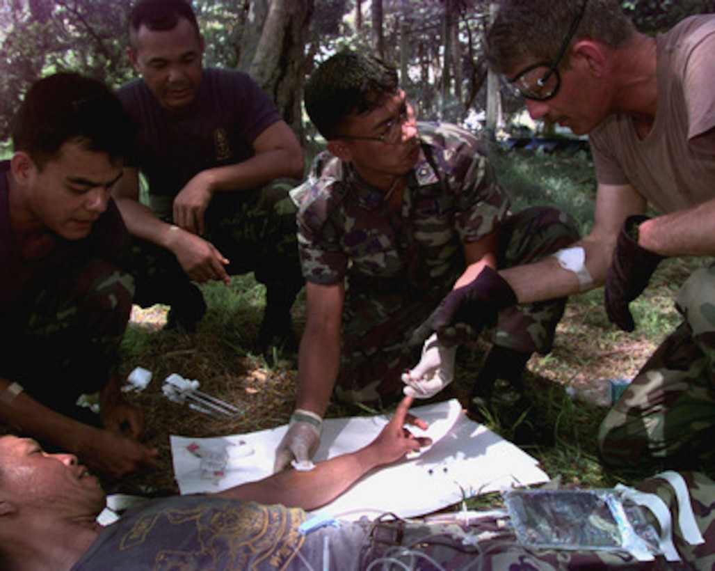 Sgt. 1st Class Brett Thorpe (right) U.S. Army, instructs Royal Thai soldiers from the 1st Special Forces Regiment, Camp Pawai, Thailand, on proper techniques of intravenous infusion on May 17, 1998, during Exercise Cobra Gold '98. Cobra Gold '98 is the latest in a continuing series of U.S.-Thai military exercises designed to ensure regional peace and strengthen the ability of the Royal Thai Armed Forces to defend Thailand. The training includes joint combined air, land and sea operations. Cobra Gold is the largest strategic mobility exercise involving the U.S. Pacific Command forces this year. Thorpe is deployed for the exercise from Special Forces Operations Detachment A-183, Fort Lewis, Wash. 