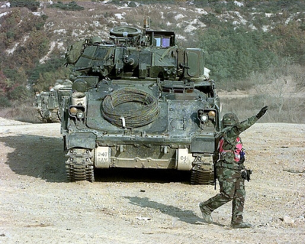 A U.S. Army soldier ground guides a M-3 Bradley Fighting Vehicle to a spot for decontamination after gunnery training at the Korea Training Center, Republic of Korea, on Oct. 25, 1998. Armored units use the range to meet yearly, live gunnery training requirements. The Bradley is attached to C Troop of the 4th Squadron, 7th Cavalry Regiment. 