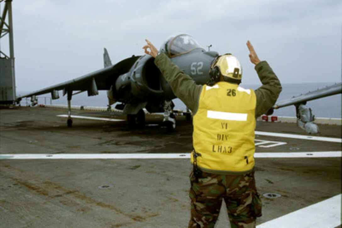 U.S. Navy Airman Arruda Keolani directs an AV-8 Harrier as it moves on the flight deck of the USS Belleau Wood (LHA 3) on Oct. 30, 1998, as the ship operates off the coast of the Republic of Korea during Exercise Foal Eagle '98. Foal Eagle '98 is a combined, joint exercise supported by forces from the U.S. and Republic of Korea. In addition to providing hands-on field experience for forces of both nations, Foal Eagle '98 was designed to test rear area protection operations and major command, control and communications systems. The Harrier is deployed onboard the Belleau Wood from Attack Squadron 311, Yuma, Ariz. 