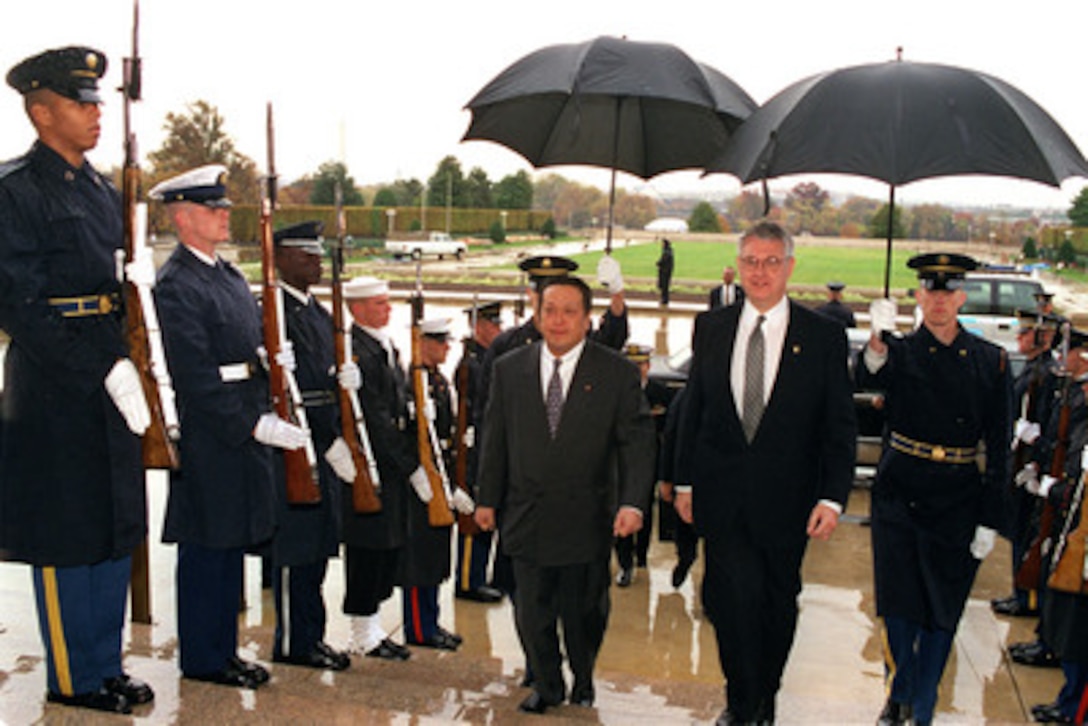Parliamentary Vice Minister Yasukazu Hamada (left), of Japan, is escorted by Deputy Secretary of Defense John J. Hamre (right) through an armed forces honor cordon into the Pentagon on Nov. 3, 1998. 