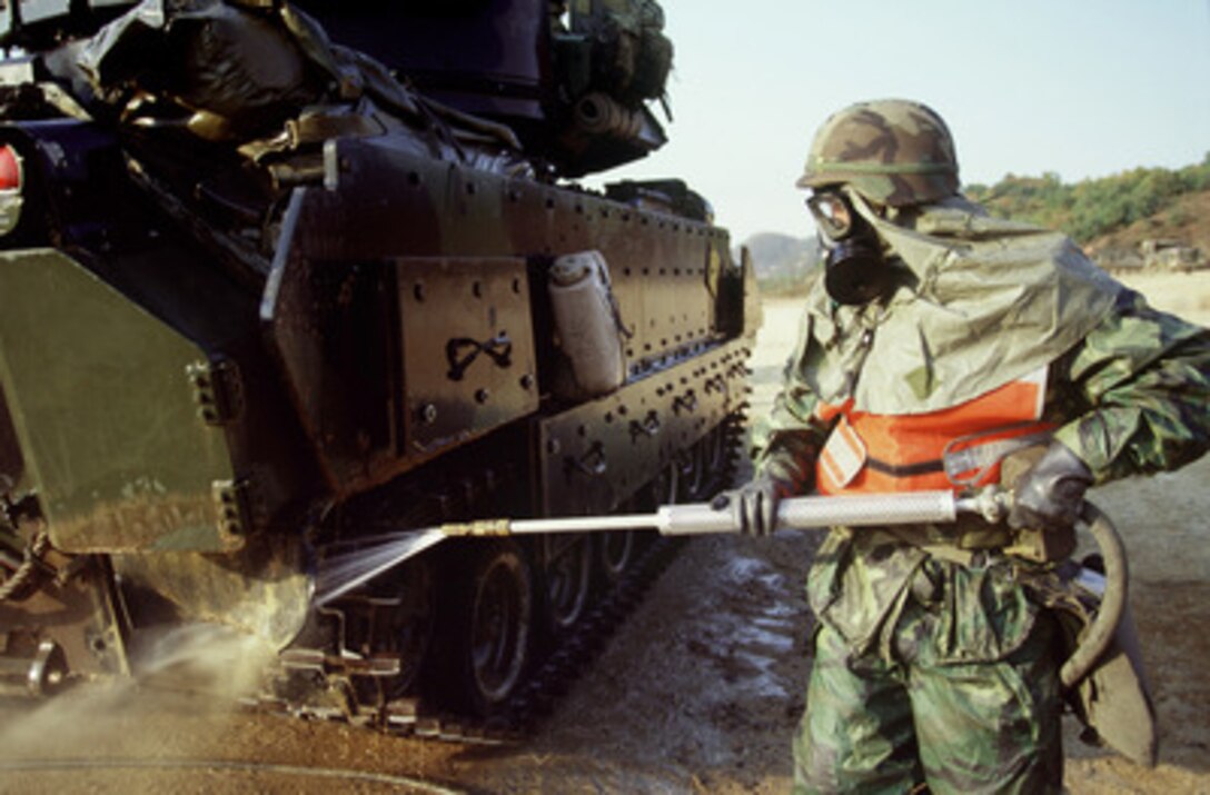 Spc. D. Shewfelt, U.S. Army, uses a pressure washing system to decontaminate an M-3 Bradley Fighting Vehicle, after gunnery training at the Korea Training Center, Republic of Korea, on Oct. 25, 1998. The decontamination is part of a chemical training exercise conducted by the Army. Shewfelt and the Bradley are attached to C Troop of the 4th Squadron, 7th Cavalry Regiment. 