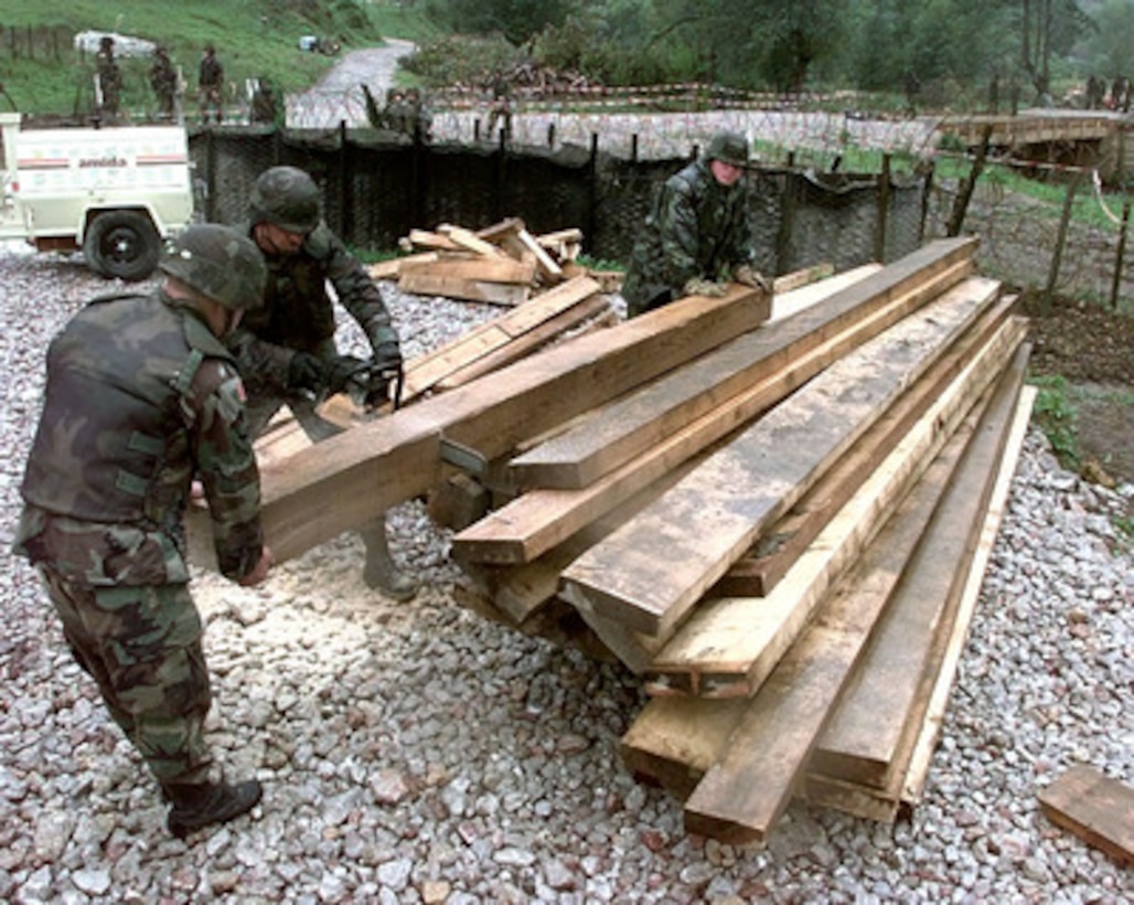 U.S. Army Combat Engineers use a chain saw to cut timber to be used to level a bridge being constructed at Camp Demi near Kladanj, Bosnia and Herzegovina, on Sept. 27, 1998. The flooding Drinjaca river damaged the supports of the present bridge leading to the American army compound which was forced to close the gate used for multi-ton vehicle traffic. The construction of the bridge is a combined effort between the U.S. Army's Alpha Company, 40th Engineers 1st Platoon of Idar Oberstein, Germany; Alpha Company 20th Engineers 2nd Platoon, of Fort Hood, Texas; Brown and Root civilian contractors and Romanian Army Engineers. The engineers are deployed to Bosnia and Herzegovina to support Operation Joint Forge. 