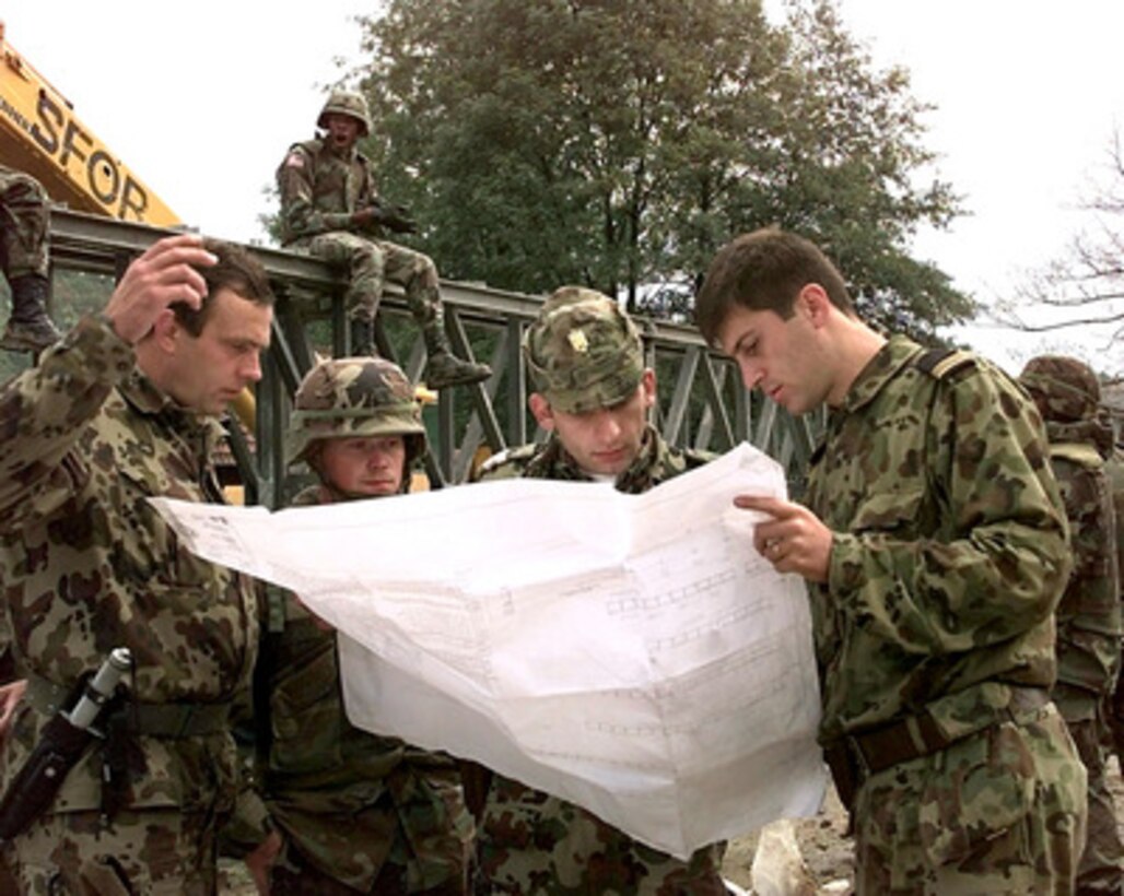 Combat engineers from the U.S. and Romanian Armies consult the blue prints as they erect a Mabey and Johnson bridge at Camp Demi near Kladanj, Bosnia and Herzegovina, on Sept. 28, 1998. The flooding Drinjaca river damaged the supports of the present bridge leading to the American army compound which was forced to close the gate used for multi-ton vehicle traffic. The construction of the bridge is a combined effort between the U.S. Army's Alpha Company, 40th Engineers 1st Platoon of Idar Oberstein, Germany; Alpha Company 20th Engineers 2nd Platoon, of Fort Hood, Texas; Brown and Root civilian contractors and Romanian Army Engineers. The engineers are deployed to Bosnia and Herzegovina to support Operation Joint Forge. 