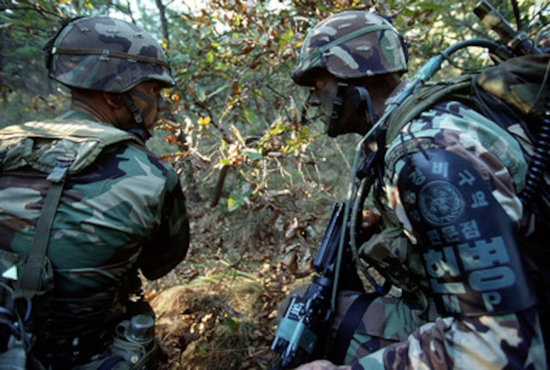 Spc. Escobedo (left) and Staff Sgt. Meegan (right) stop to discuss the next maneuver during a regular patrol of the Demilitarized Zone in the Republic of Korea, on Oct. 20, 1998. Escobedo and Meegan are assigned to the Joint Security Area Scout Platoon. The patrol is part of a Quick Reaction Force that is positioned in the zone to respond to any situations that may arise. These U.S. Army soldiers are attached to the United Nations Command Security Battalion. 