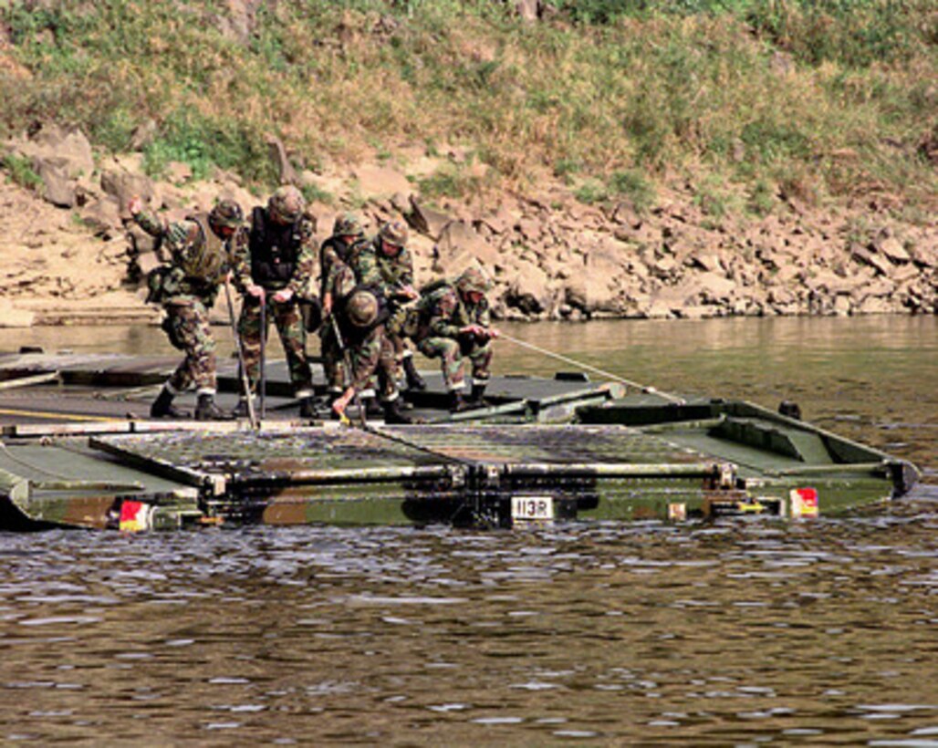 Soldiers assigned to the 50th Engineer Company, 1st Platoon, and the 2nd Battalion, 9th Infantry, use muscle to pull together two sections of pontoon bridge on the Imjin River in the Republic of Korea, during a bridge building training exercise on Oct. 22, 1998. Soldiers assigned to the 50th Engineer Company, 1st Platoon, and the 2nd Battalion, 9th Infantry, are participating in the exercise as part of the U.S. Army Officer Professional Development Program, which is designed to improve team building and soldiery. The 50th Engineers are from Camp Laguardia and the 9th Infantry are from Camp Casey in the Republic of Korea. 