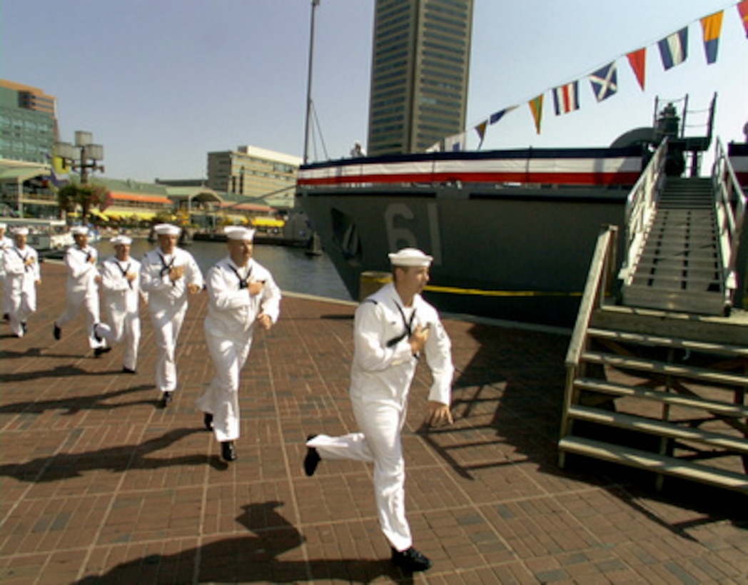 Crew members from the U.S. Navy's newest mine warfare ship USS Raven (MHC 61) hold their medals as they run on board to bring the ship to life during commissioning ceremonies in Baltimore, Md., on Sept. 5, 1998. 