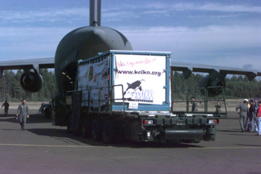 An Air Force 60K Tunner cargo loader approaches a C-17 Globemaster III in preparation for loading the specially made transport tank containing Keiko, the killer whale star of the "Free Willy" movie, at the Newport Municipal Airport in Newport, Oregon, on Sept. 9, 1998. Keiko was loaded into his specially made transport tank at the Oregon State Aquarium, then transported by United Parcel Service to the airport. The aircraft from the 15th Airlift Squadron and its killer whale cargo will fly nonstop to the Westman Islands in Iceland. The Free Willy Keiko Foundation is paying the Air Force to airlift the whale back to his native waters. The C-17 Globemaster III is the only aircraft that can accomplish moving such a large load and deliver it to a short, remote runway. 