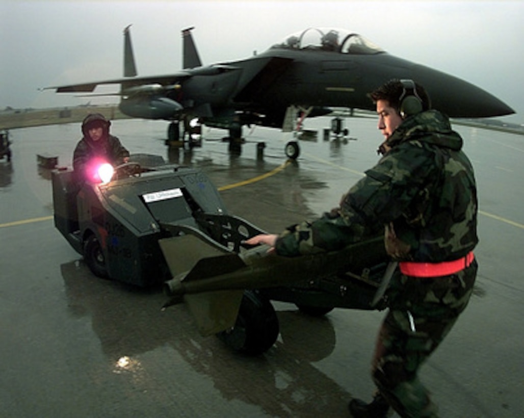 Senior Airman Aaron Fontagneres (left) and Staff Sgt. John Rodriguez (right) work in the pouring rain to load an MK-82 bomb on an F-15E Strike Eagle at Aviano Air Base, Italy, on April 7, 1999, in preparation for a mission supporting NATO Operation Allied Force. Operation Allied Force is the air operation against targets in the Federal Republic of Yugoslavia. Fontagneres and Rodriguez are deployed to Aviano with the 494th Fighter Squadron, RAF Lakeneath, United Kingdom. 