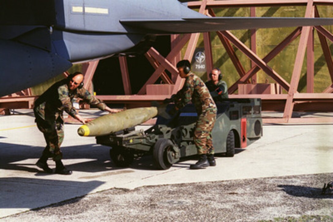 U.S. Air Force Staff Sgt. Matthew Treff (left), Senior Airman Edward Cunningham (center) and Senior Airman Damon Cipolla (right) load bombs onto an F-15 Fighter at Aviano Air Base, Italy on April 9, 1999, in preparation for a mission supporting NATO Operation Allied Force. Operation Allied Force is the air operation against targets in the Federal Republic of Yugoslavia. Treff, Cunningham and Cipolla are Weapons Armament Systems Specialists attached to the 48th Fighter Squadron. 