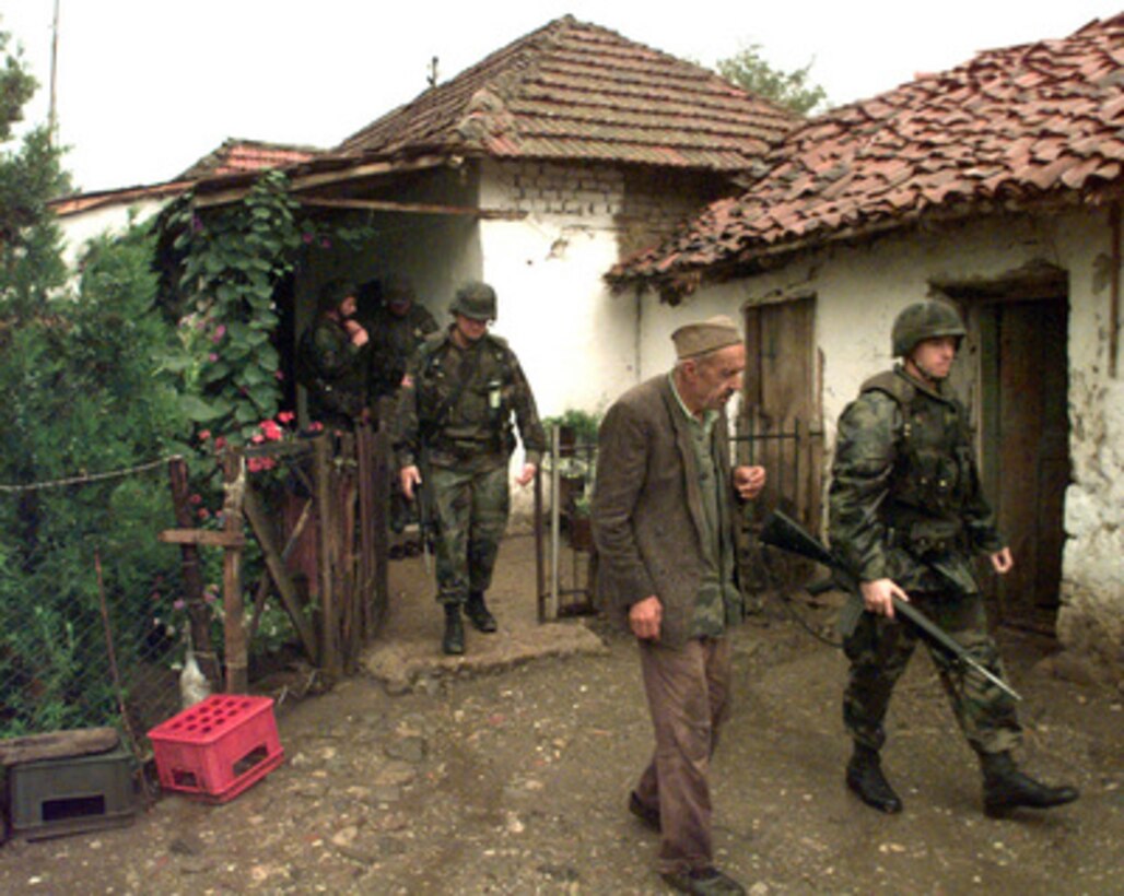 U.S. Army 1st Lt. James Perrine (right) escorts a Serbian citizen from his home in Zitinje, Kosovo, after finding an automatic weapon and a Russian side arm on July 26, 1999. Soldiers of the 1st Battalion, 7th Field Artillery are searching for automatic weapons in the town. Perrine and other soldiers of the 7th are deployed to Kosovo as part of KFOR. KFOR is the NATO-led, international military force in Kosovo on the peacekeeping mission known as Operation Joint Guardian. 