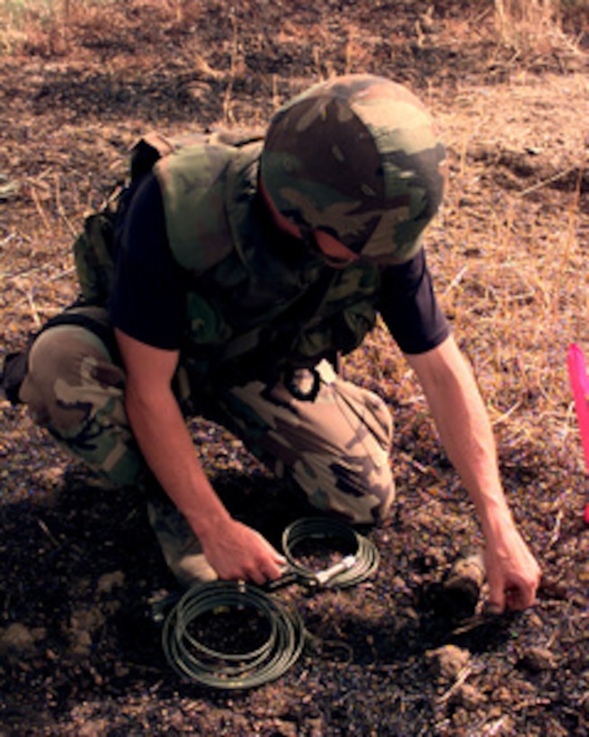 Senior Airman Timothy Stimpson, U.S. Air Force, prepares an unexploded BLU-97 bomblet for demolition in a field outside of Urosevac, Kosovo, on Aug. 10, 1999. Stimpson is from the 4th Civil Engineer's Squadron (Explosive Ordnance Disposal), Seymour Johnson Air Force Base, N.C., and is deployed to Kosovo as part of KFOR. KFOR is the NATO-led, international military force in Kosovo on the peacekeeping mission known as Operation Joint Guardian. 