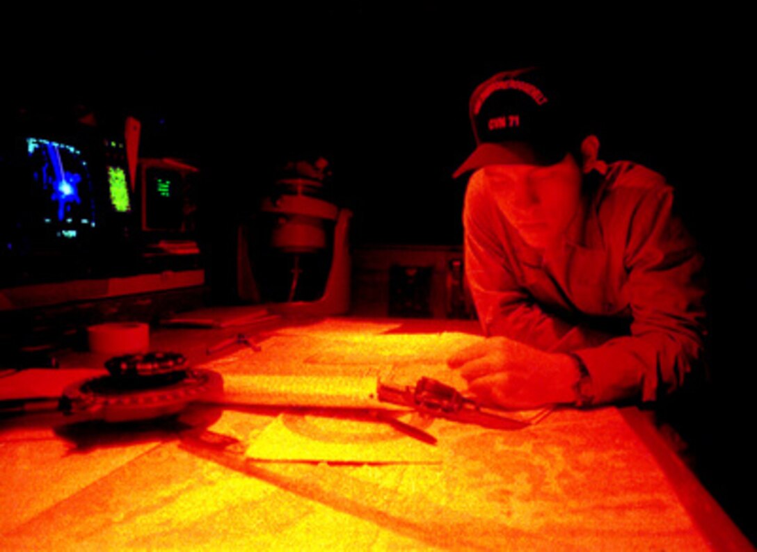 Seaman Apprentice Timothy Lee, U.S. Navy, works in the glow of red light at the chart table on the bridge of the USS Theodore Roosevelt (CVN 71) on Aug. 31, 1999. The aircraft carrier is transiting the Red Sea at night en route to the Suez Canal. The red light preserves the night vision of the crew. Lee, from Baltimore, Md., is a Navy quartermaster. 