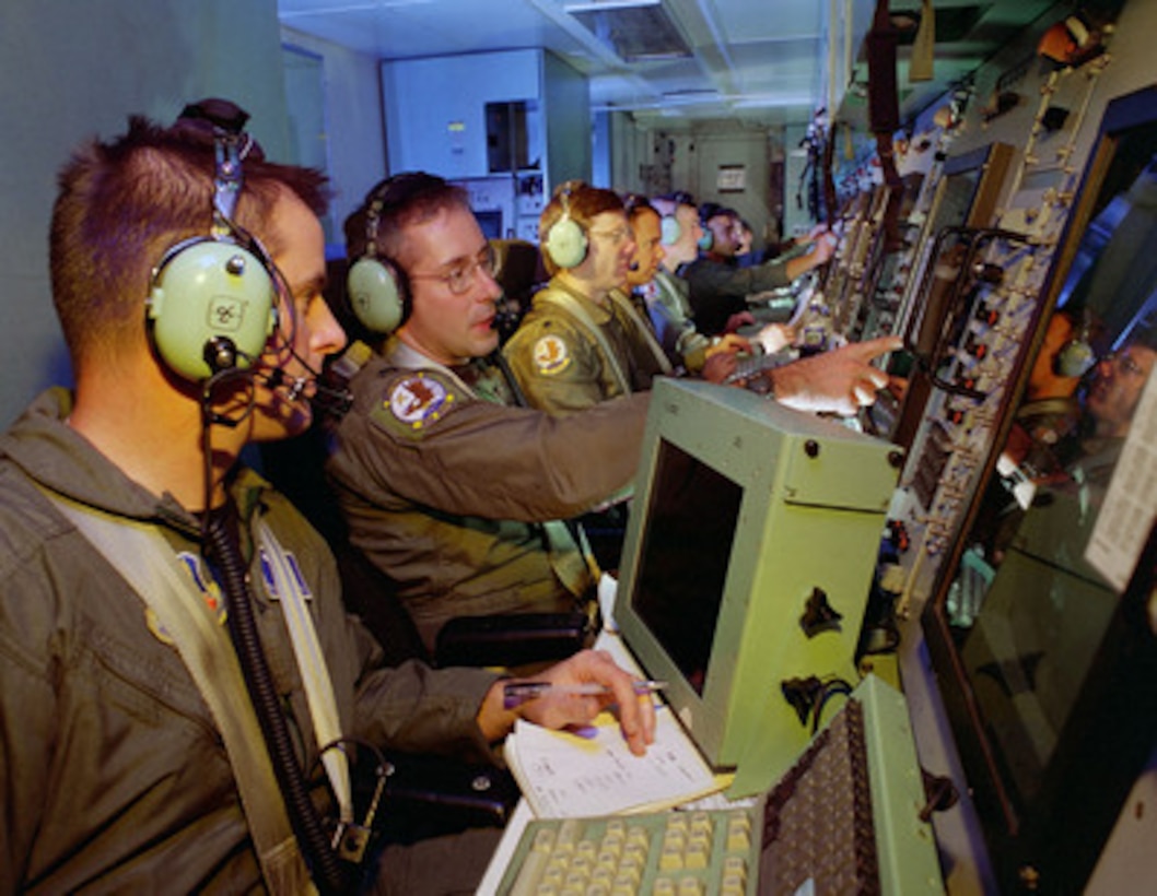 Airborne intelligence technician Tech. Sgt. Craig Webster (left) and airborne intelligence officer Capt. Chris Roberts (2nd from left) work during a training mission in an EC-130E Airborne Battlefield Command and Control Center over Tucson, Ariz., on Dec. 19, 1999. They are flying aboard a USC-48 Airborne Battlefield Command and Control Center capsule which fits into the aircraft cargo compartment of a modified EC-130E aircraft. The system is a high-tech, automated airborne command and control facility featuring computer generated color displays, digitally controlled communications, and rapid data retrieval. The platform's 23 fully securable radios, secure teletype, and 15 automatic fully computerized consoles, allow the battle staff to quickly analyze current combat situations and direct offensive air support towards fast-developing targets. Webster, of Ford City, Pa., and Roberts, of Ontario, Calif., are attached to the 42nd Airborne Command and Control Squadron, Davis-Monthan Air Force Base, Ariz. 
