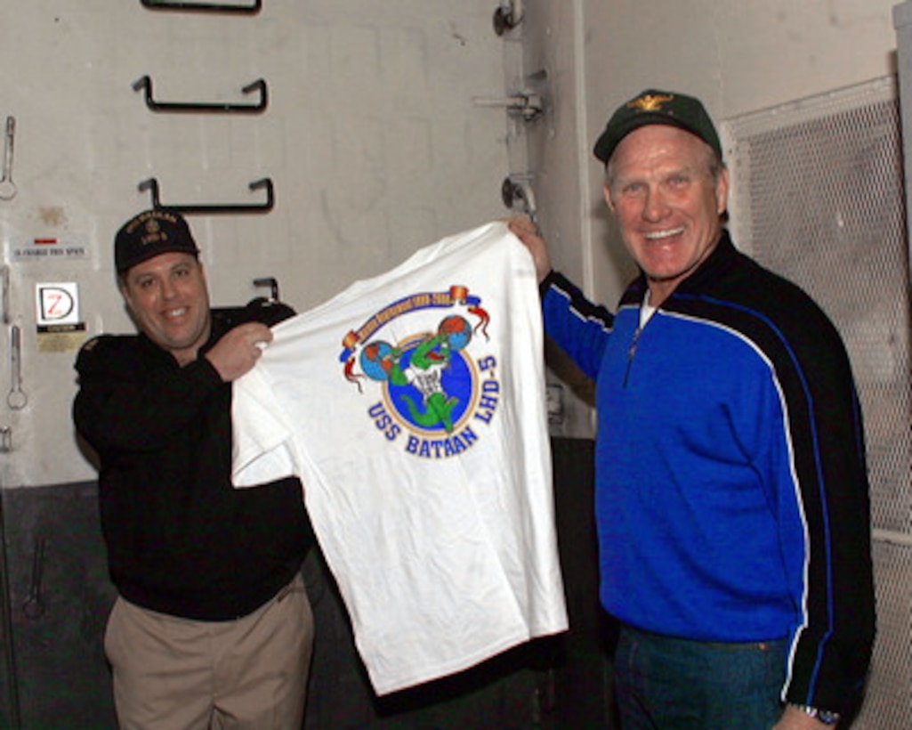 ABOARD USS BATAAN (December 21, 1999) - Chief Electrician's Mate Daniel C. Stonebraker gives a USS Bataan tee shirt to Fox Sportscaster and former pro quarterback Terry Bradshaw during a Christmas USO Show held aboard the landing helicopter dock ship USS Bataan (LHD 5). Bradshaw was one of many celebrities in the show hosted by U.S. Secretary of Defense William S. Cohen. Cohen's stop aboard Bataan was the first of several visits to military units operating through southern Europe and the Balkans during the Christmas and New Year's holiday season. 