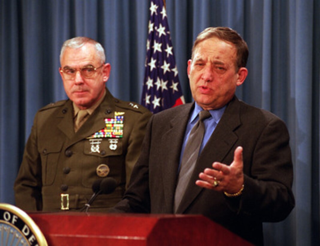 Principal Deputy Under Secretary of Defense for Acquisition, Technology and Logistics David Oliver (right) briefs reporters at the Pentagon on the current status of the anthrax immunization program for the U.S. armed services on Dec. 13, 1999. Joining him on the podium is Maj. Gen. Randall L. West, U.S. Marine Corps, who is the special advisor on anthrax and biological defense matters to the Under Secretary of Defense for Personnel and Readiness. 